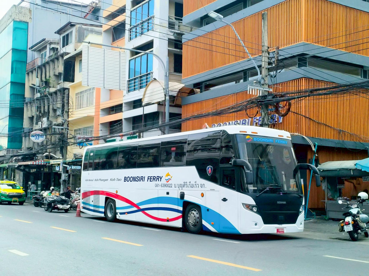 White Boonsiri Ferry coach with red and blue stripes parked on a city street