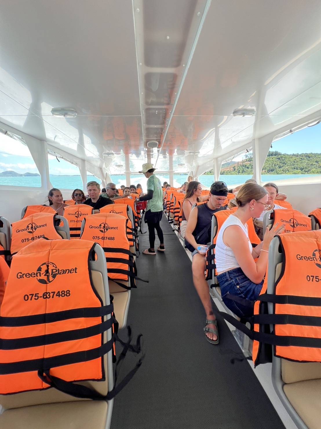 People on a boat with orange life vests and a scenic background