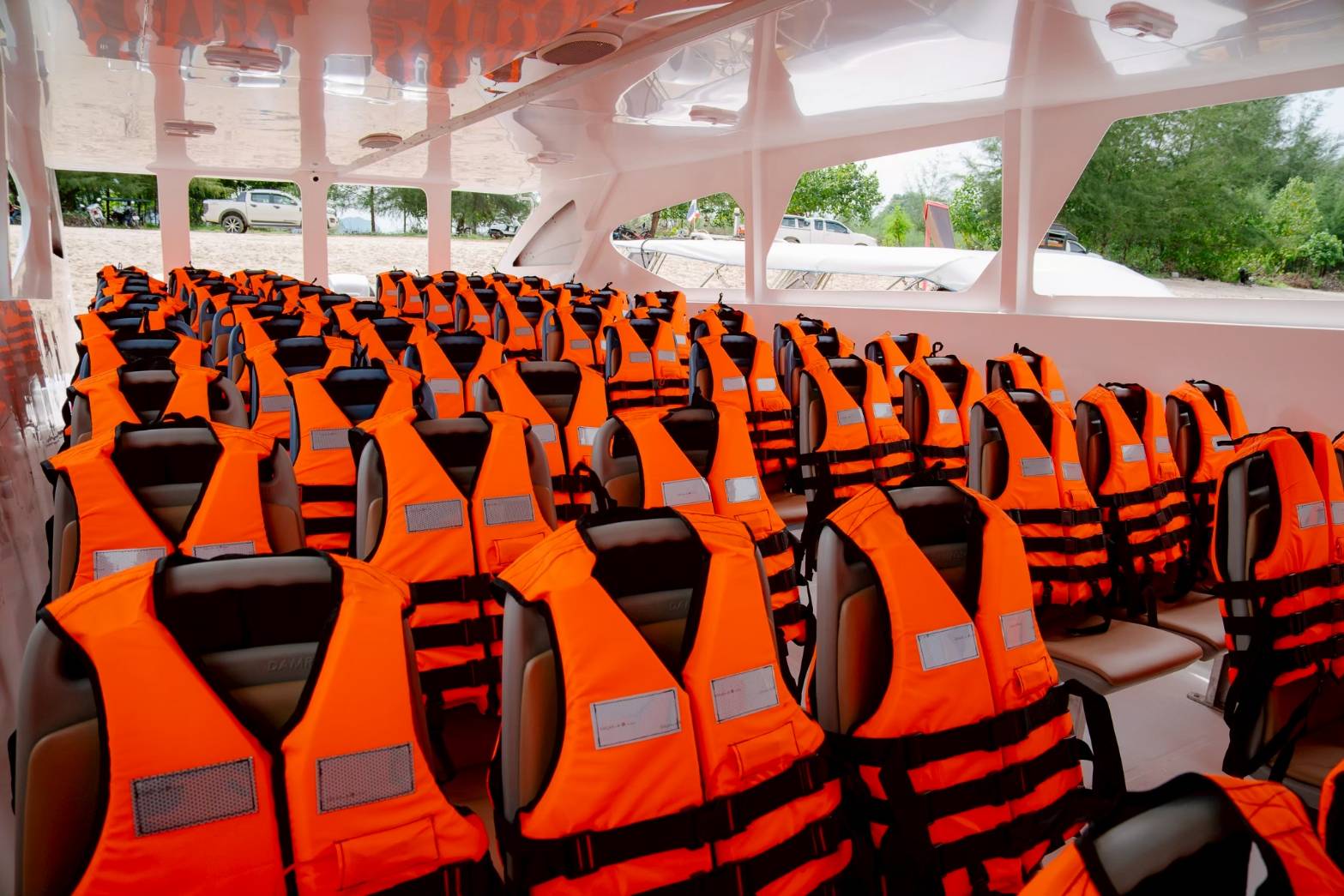 Row of orange life vests on a boat interior with seats.