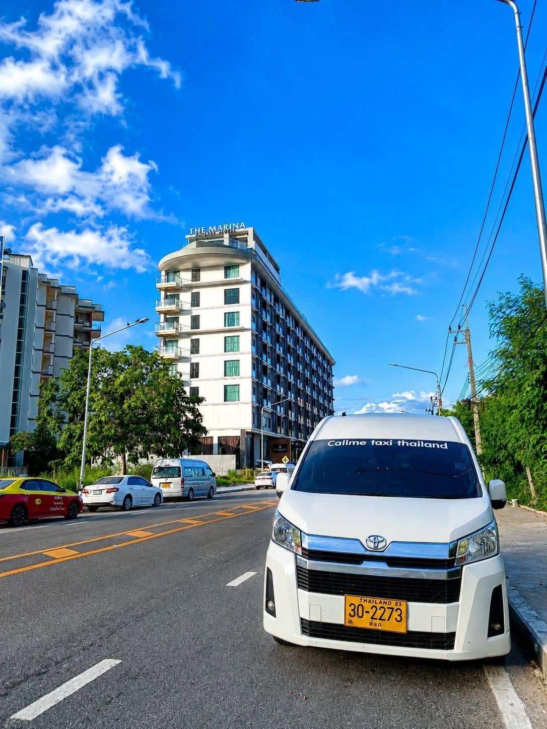 White Call me Taxi Thailand passenger van parked beside a road