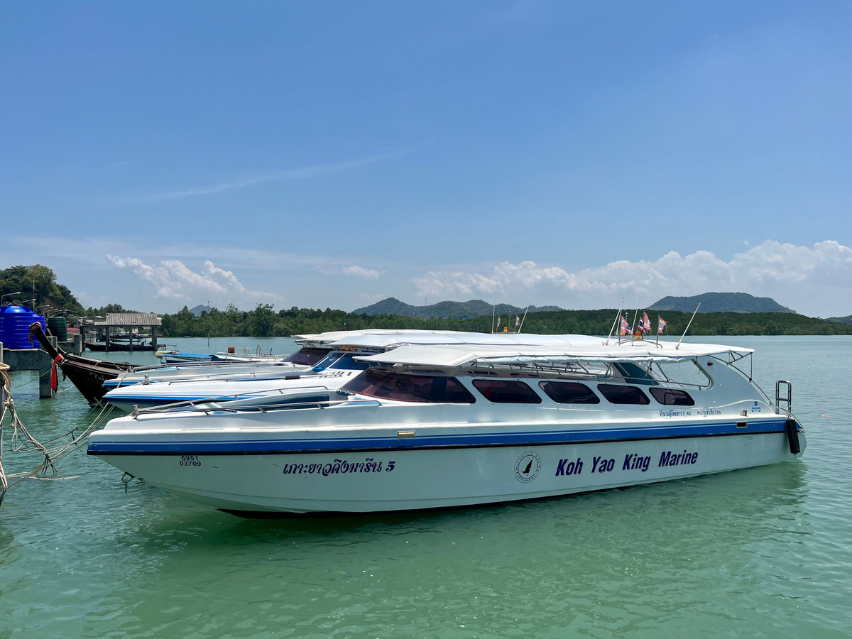 White and blue Koh Yao King Marine speedboat moored beside other boats