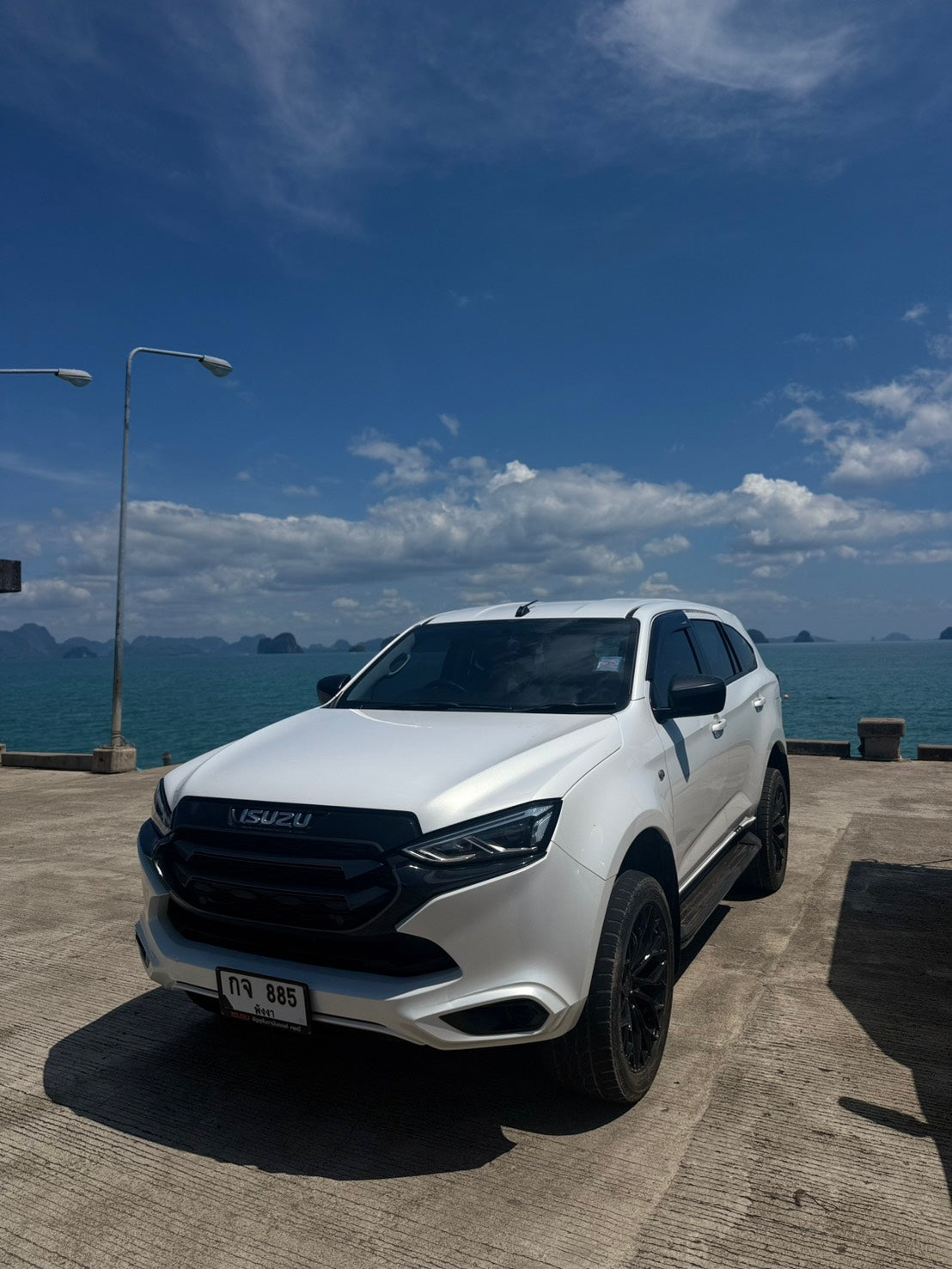 White Isuzu SUV parked at Klong Hia Pier, Koh Yao Yai, with sea view and islands in the background – Koh Yao Yai transfer