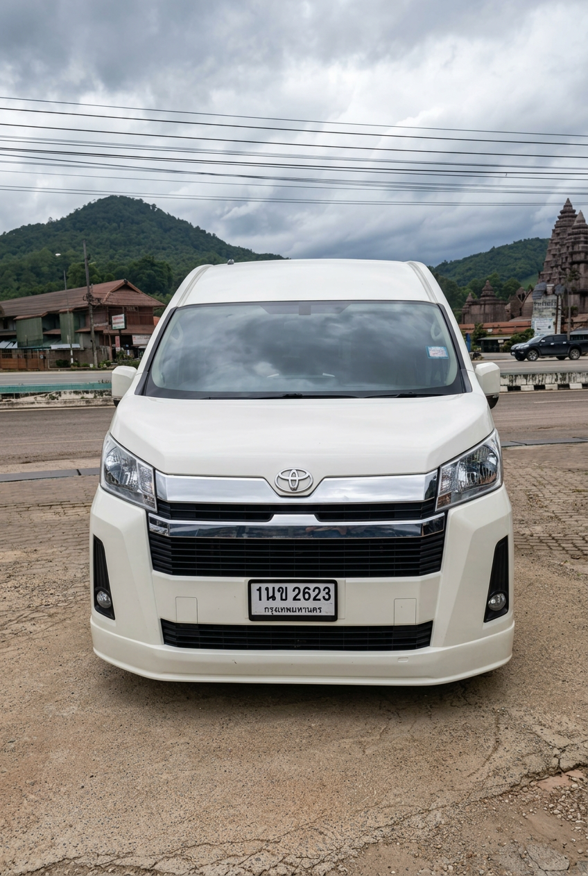 Front view of a white Toyota passenger van parked with green hills in the background