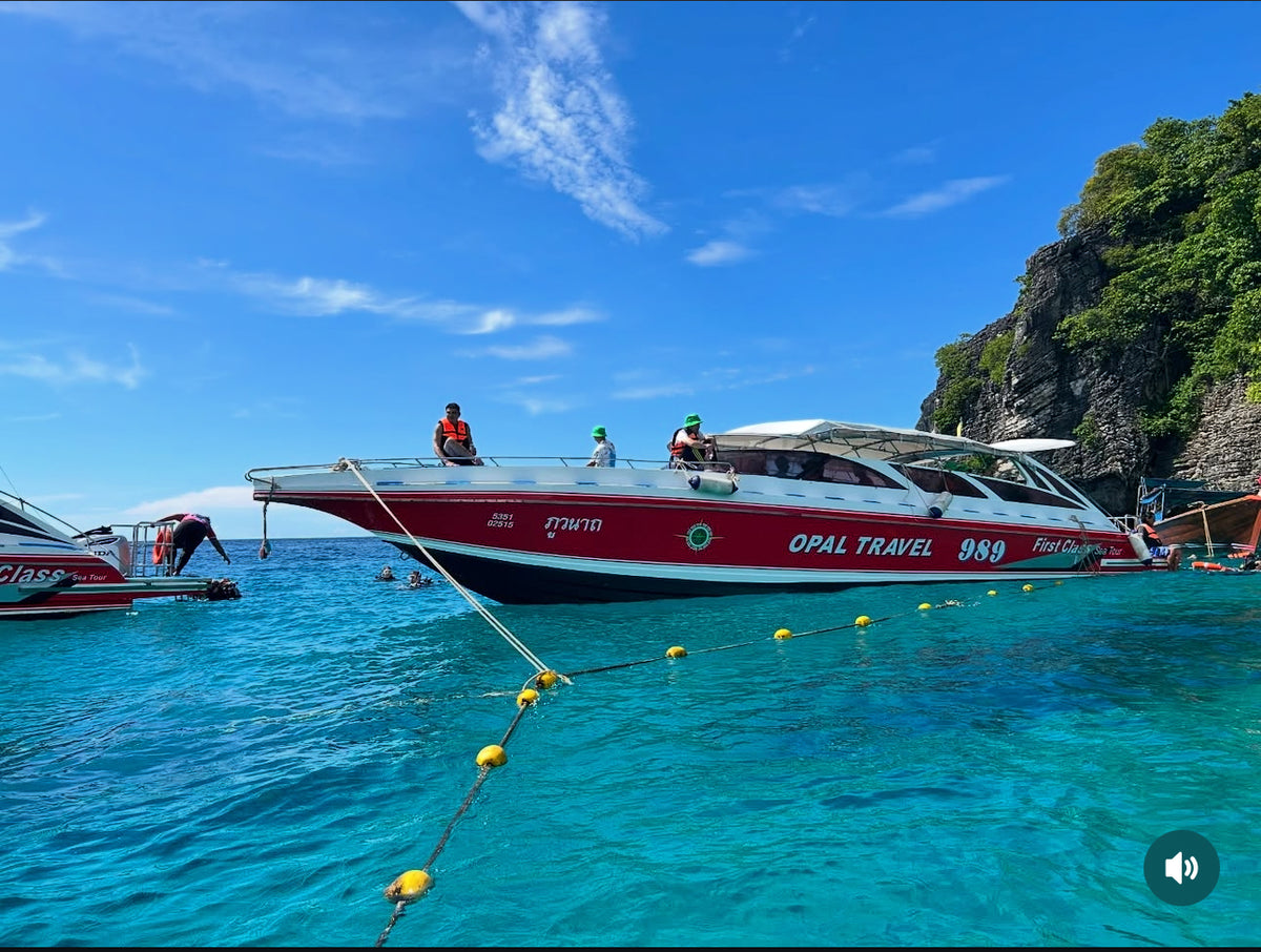 Boat with 'Opal Travel' on a clear blue sea with rocky cliffs in the background