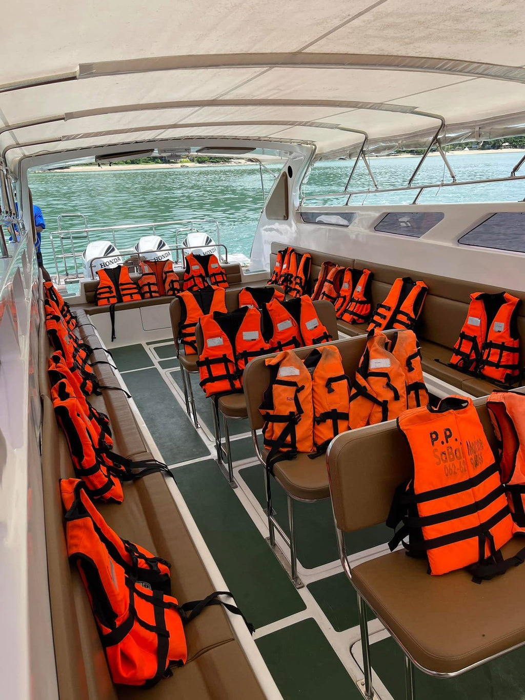 Orange life vests on a boat with a view of water through the windows.