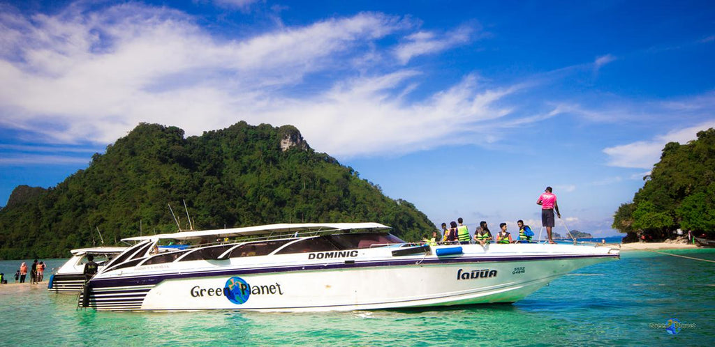 Speedboat with 'Green Planet' branding on a clear blue sea with tropical island in the background