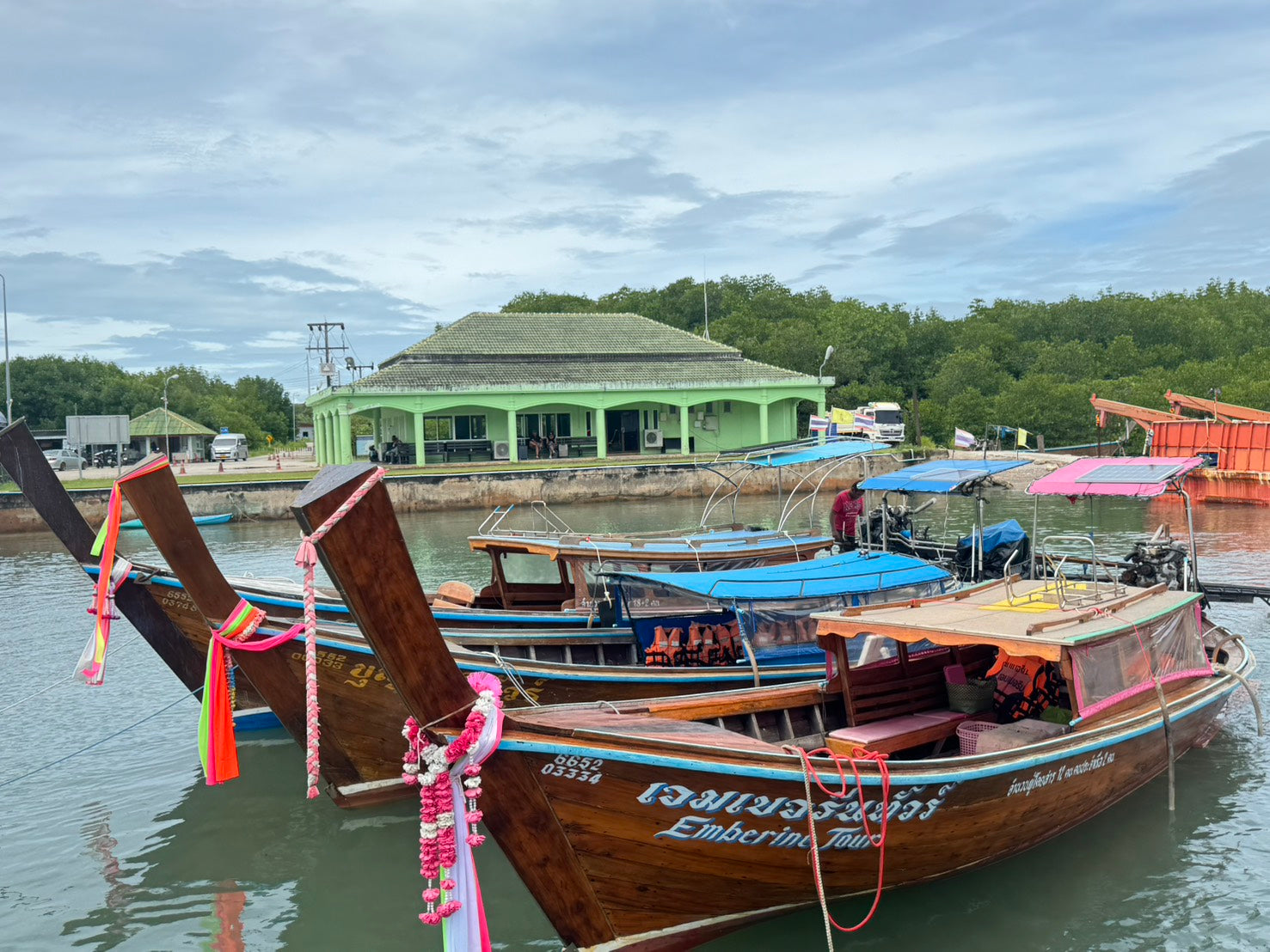 Three traditional wooden boats tied together in a harbor with a scenic background.